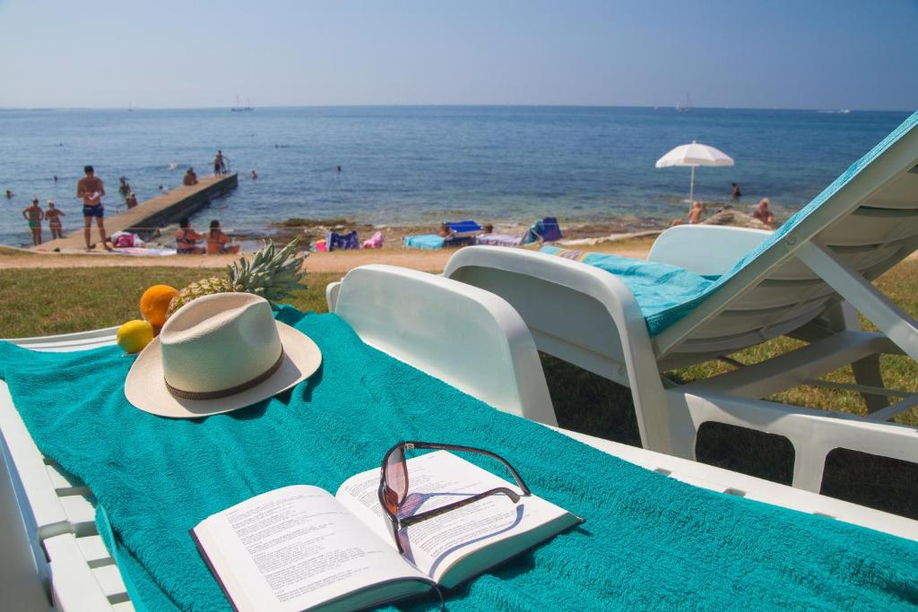 a table with a hat and a book on a beach at Apartments Erica Lux in Novigrad Istria