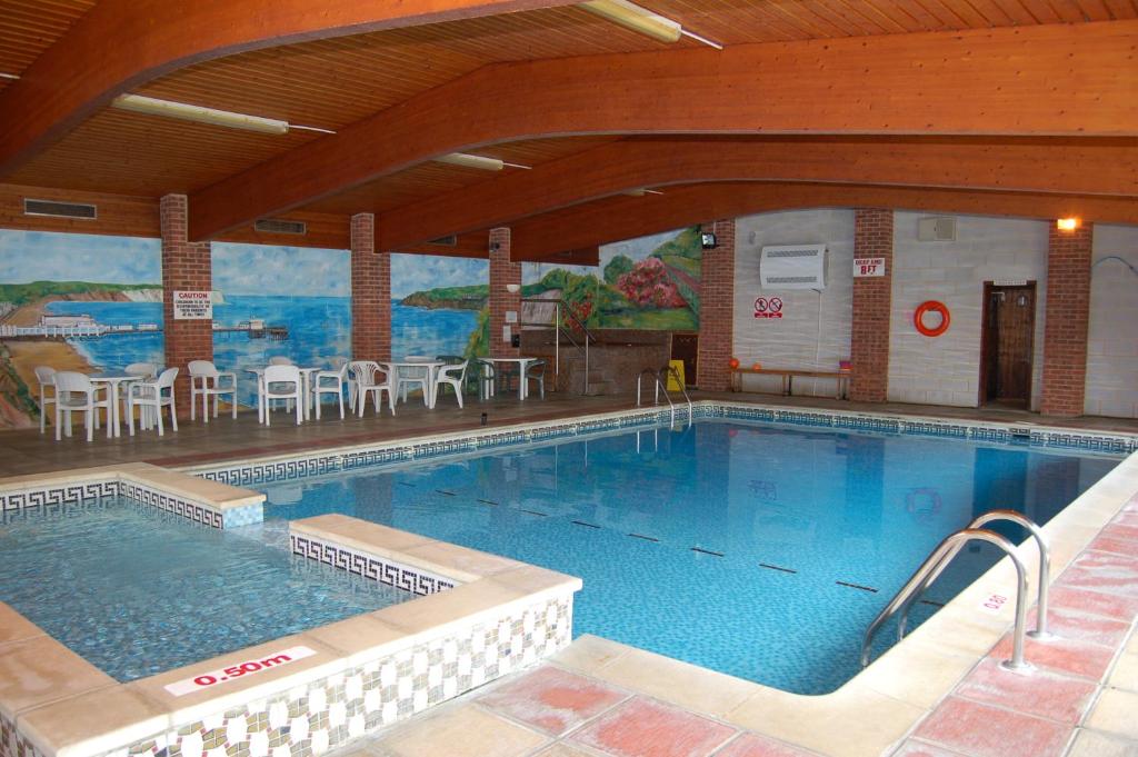 a large swimming pool with tables and chairs in a building at The Wight in Sandown