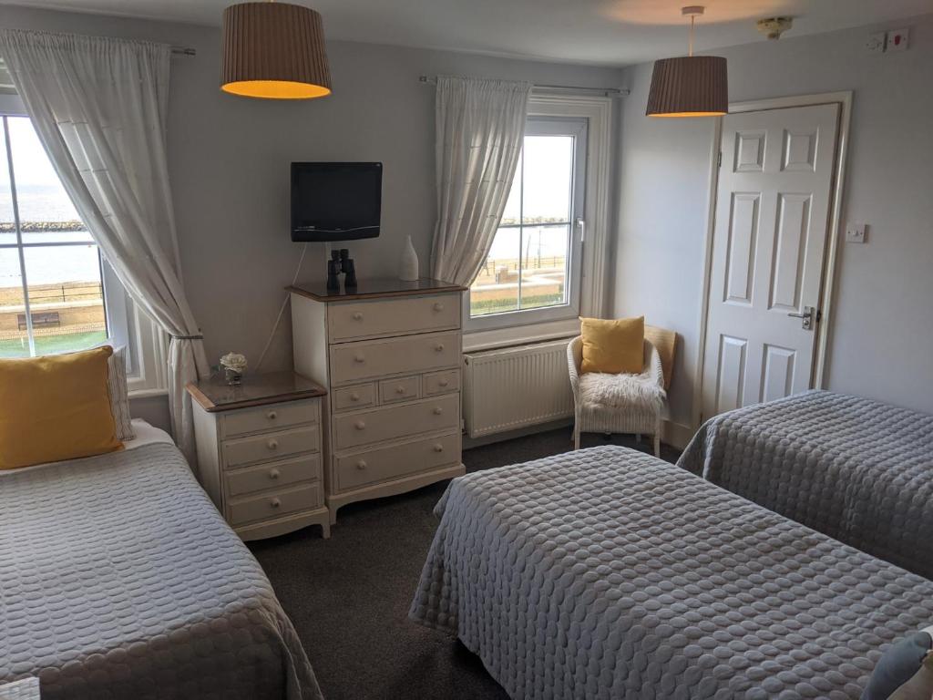 
a hotel room with two beds and a television at Aqua Bay Guest House in Herne Bay
