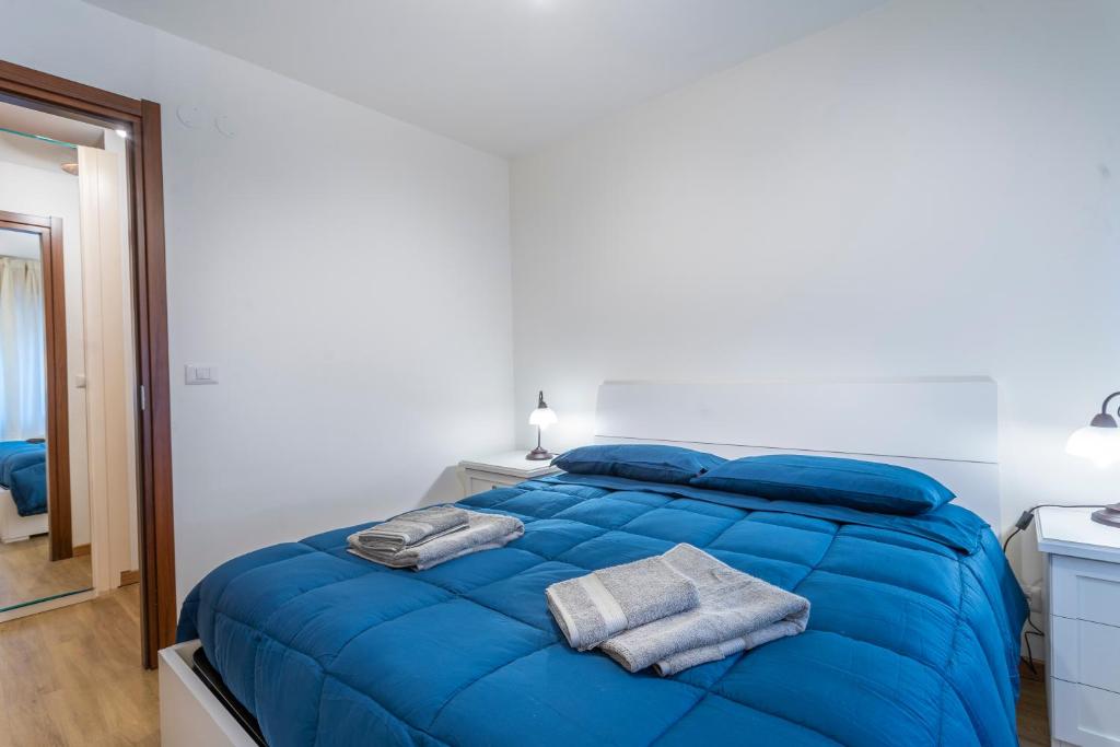 un letto blu in una stanza bianca con asciugamani di Moderno Appartamento Tarvisio - A due passi dalla Ciclovia! a Tarvisio