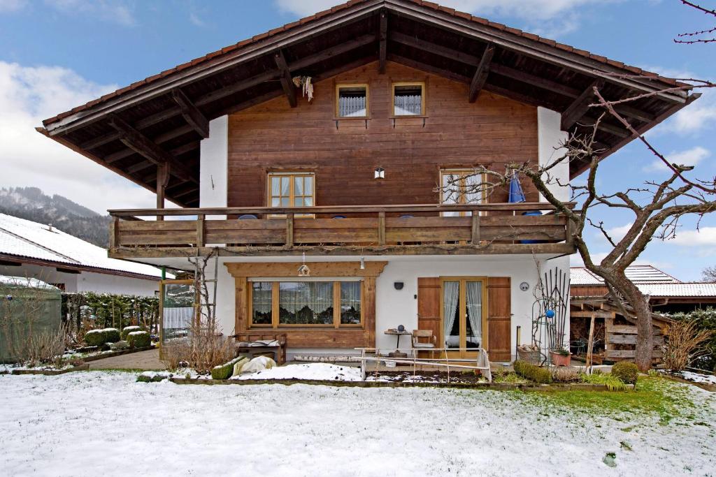 een houten huis in de sneeuw met een boom bij Ferienwohnungen Holzner klein in Inzell