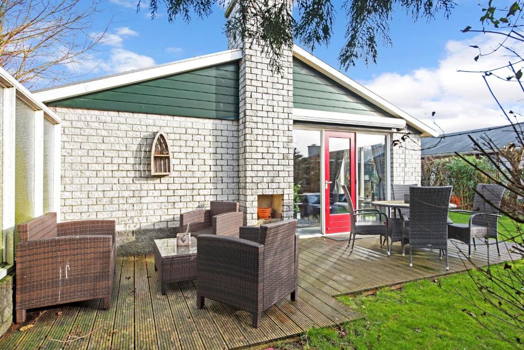 a wooden deck with chairs and a table and a house at Ferienhaus Petten aan Zee in Petten