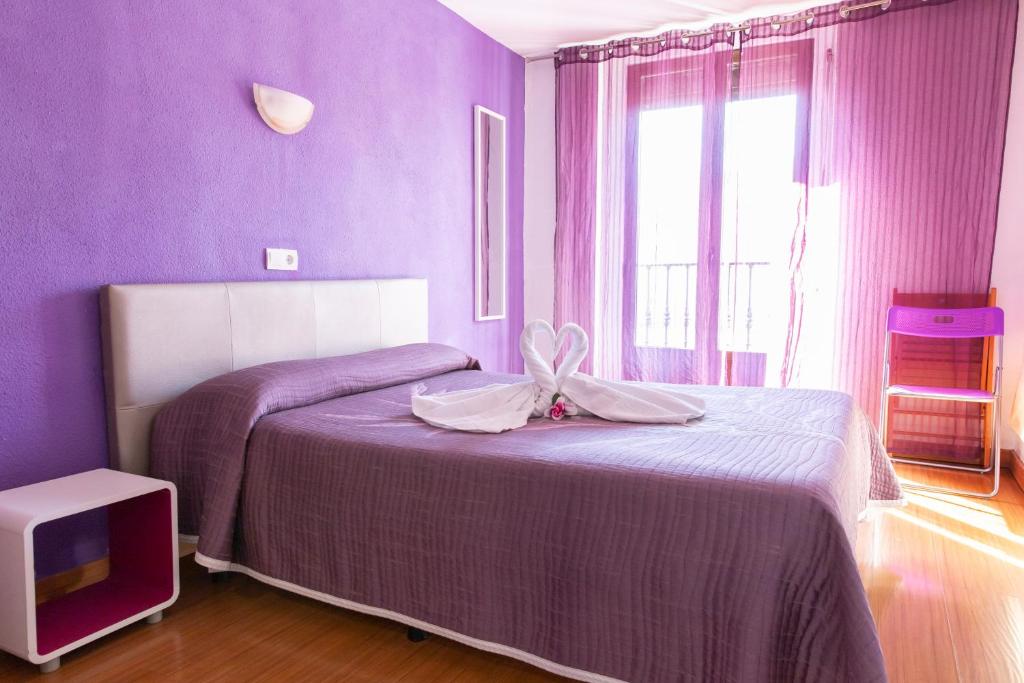 Dormitorio púrpura con cama y TV en Hostal Rober, en Madrid