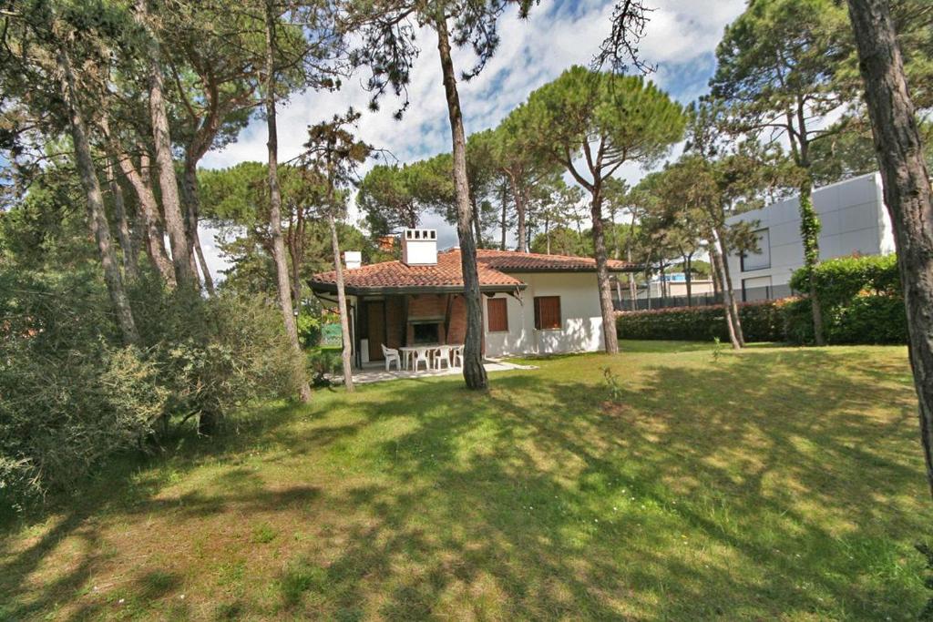 una casa in mezzo a un cortile con alberi di BA - VILLA LUCY - Single Villa - a Lignano Sabbiadoro