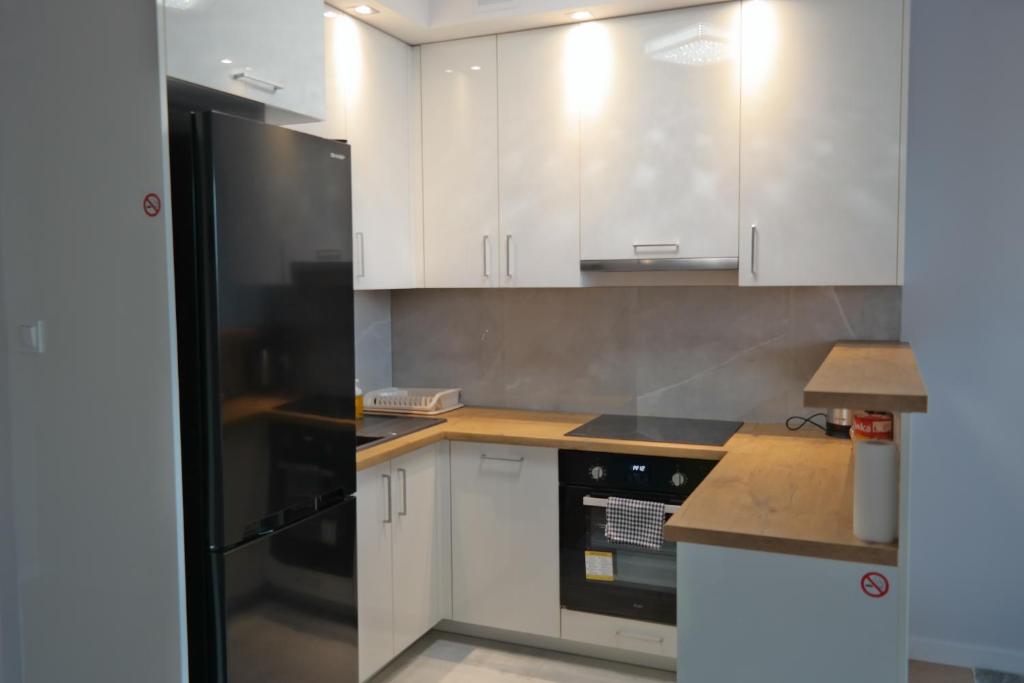 een keuken met witte kasten en een zwarte koelkast bij Apartament al. Solidarności in Białystok