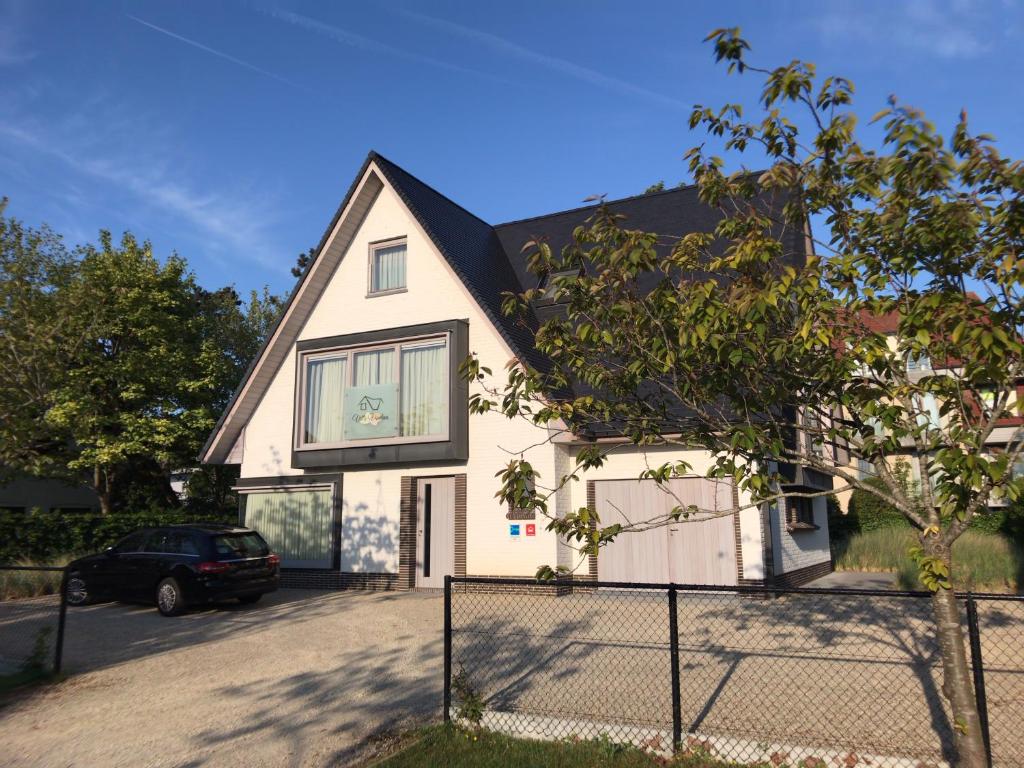 ein weißes Haus mit einem Auto in der Einfahrt in der Unterkunft Villa Vindina in De Panne