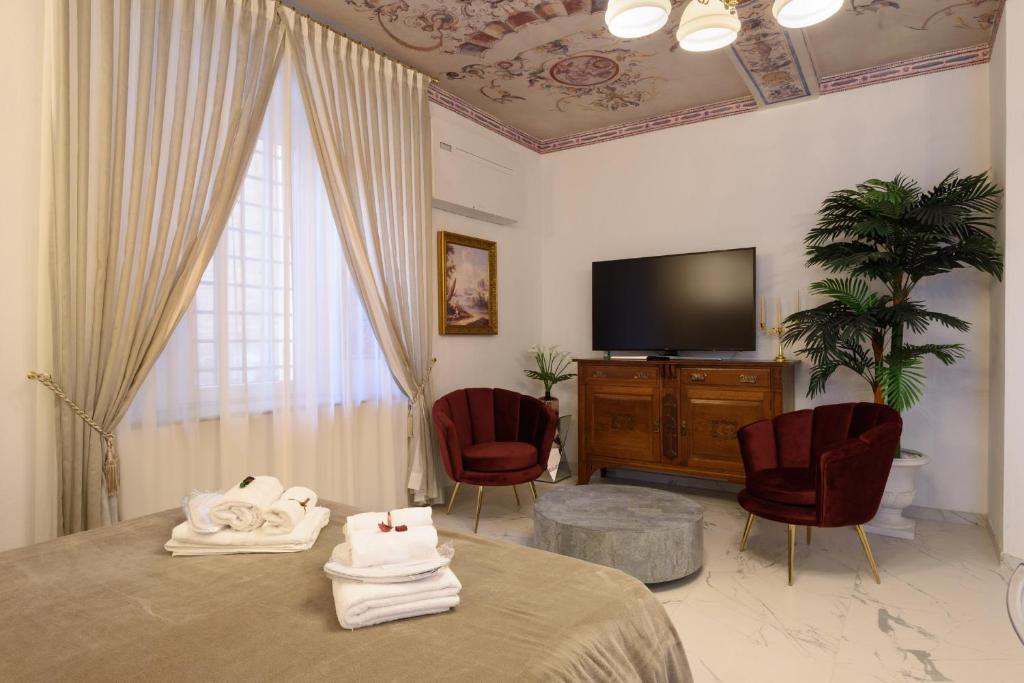 um quarto com uma cama e 2 cadeiras e uma televisão em Domus Nannini SPA - L' Arco di Matteotti em Siena