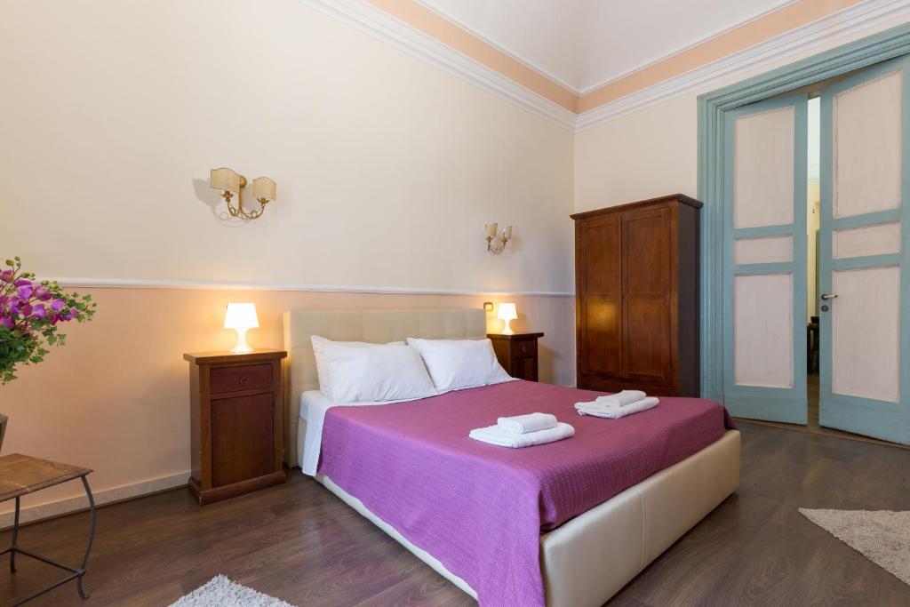 カターニアにあるB&B テアトロ ベリーニのベッドルーム(紫の毛布付きのベッド1台付)