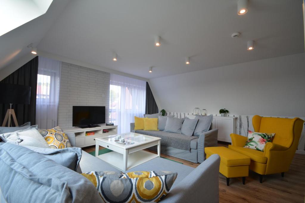una sala de estar con sofás azules y sillas amarillas. en Willa Wiesia Rabka Zdrój en Rabka