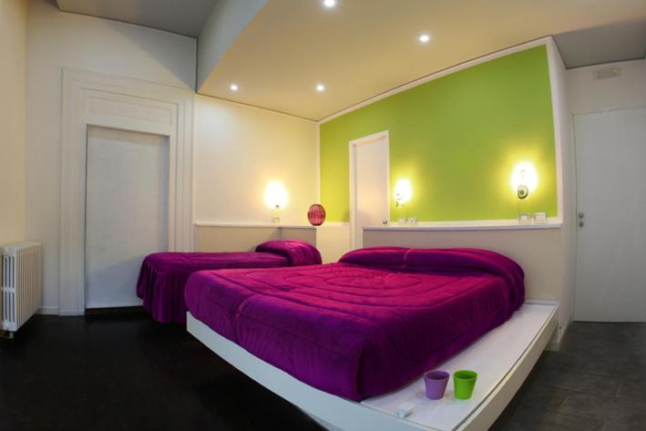 1 dormitorio con 2 camas con sábanas moradas y pared verde en The Fresh Glamour Accommodation, en Nápoles
