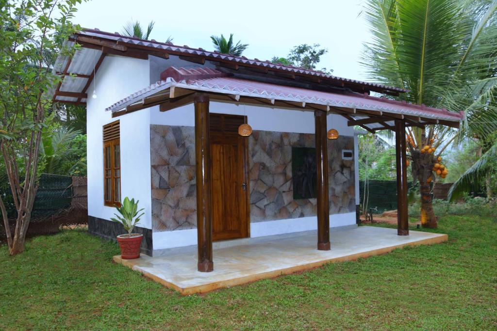 una pequeña casa con un porche en un patio en Dew Safari Cottage, en Udawalawe