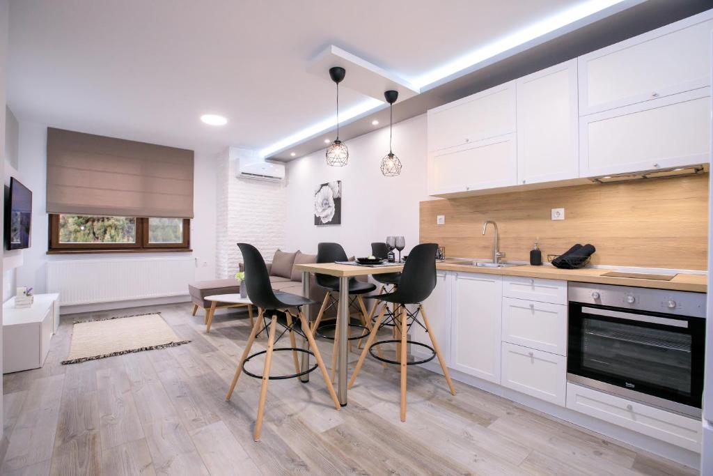 サンダンスキにあるBabylon Park Apartmentの白いキャビネット、テーブルと椅子付きのキッチンが備わります。