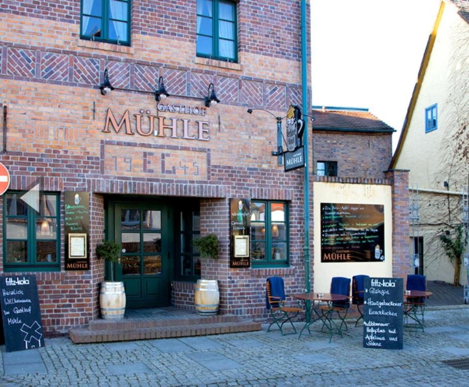 a brick building with a restaurant with tables and chairs at Gasthof Mühle in Lübbenau