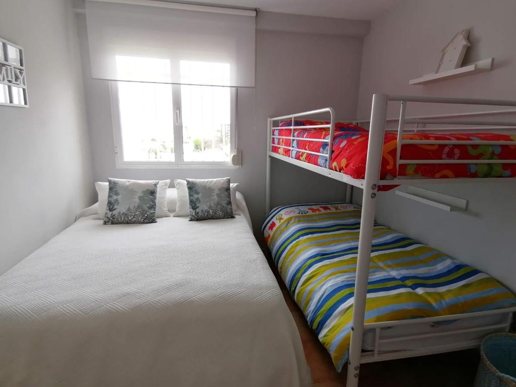 a small bedroom with two bunk beds and a window at APARTAMENTO PLAYA DE REGLA, Chipiona, primera linea in Chipiona