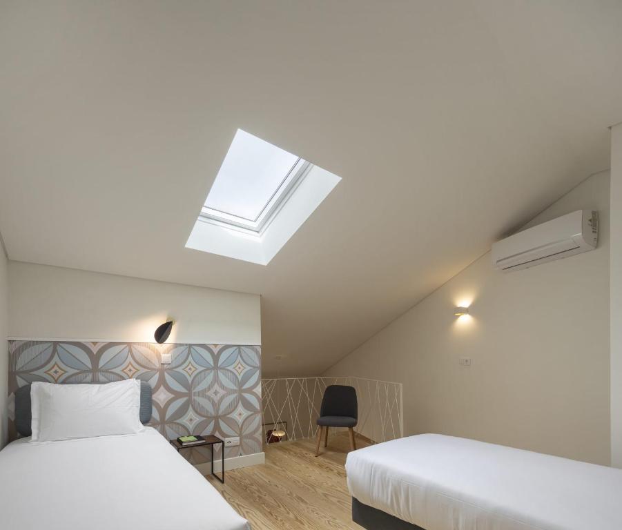 a attic bedroom with two beds and a skylight at Lisbon Serviced Apartments - Santos in Lisbon