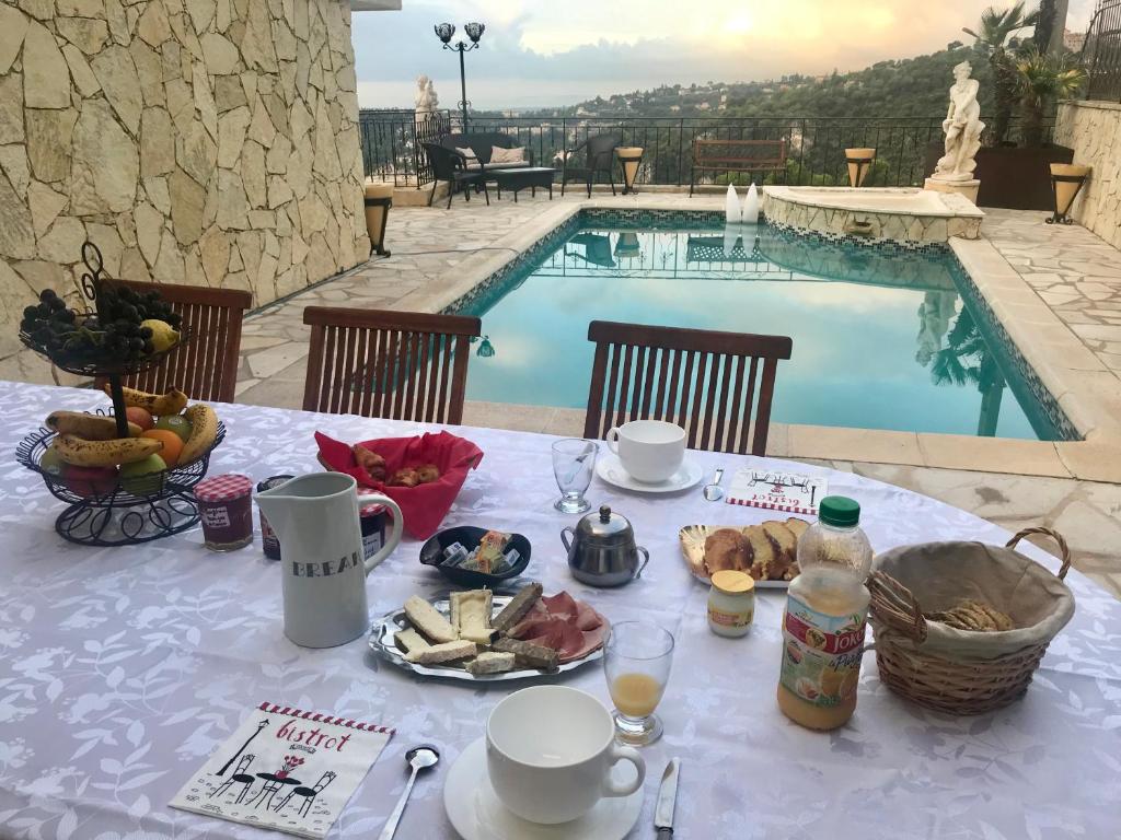 a table with food and drinks next to a swimming pool at Chambres chez l'habitant Villa l'Île aux Anges in Saint-Andre-de-la-Roche