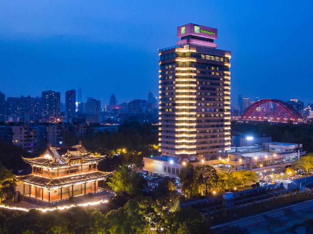 Holiday Inn Wuhan Riverside, an IHG Hotel في ووهان: مبنى طويل مع علامة عليه في الليل