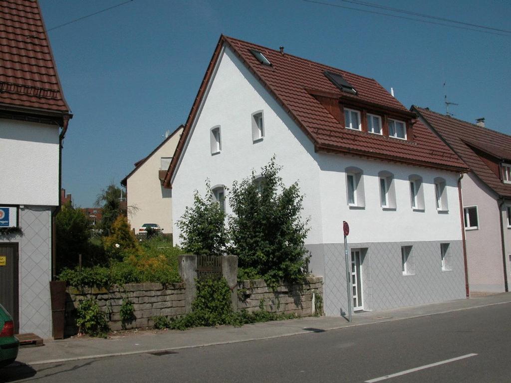 una casa blanca con techo rojo en una calle en Das Apartmenthaus, en Stuttgart