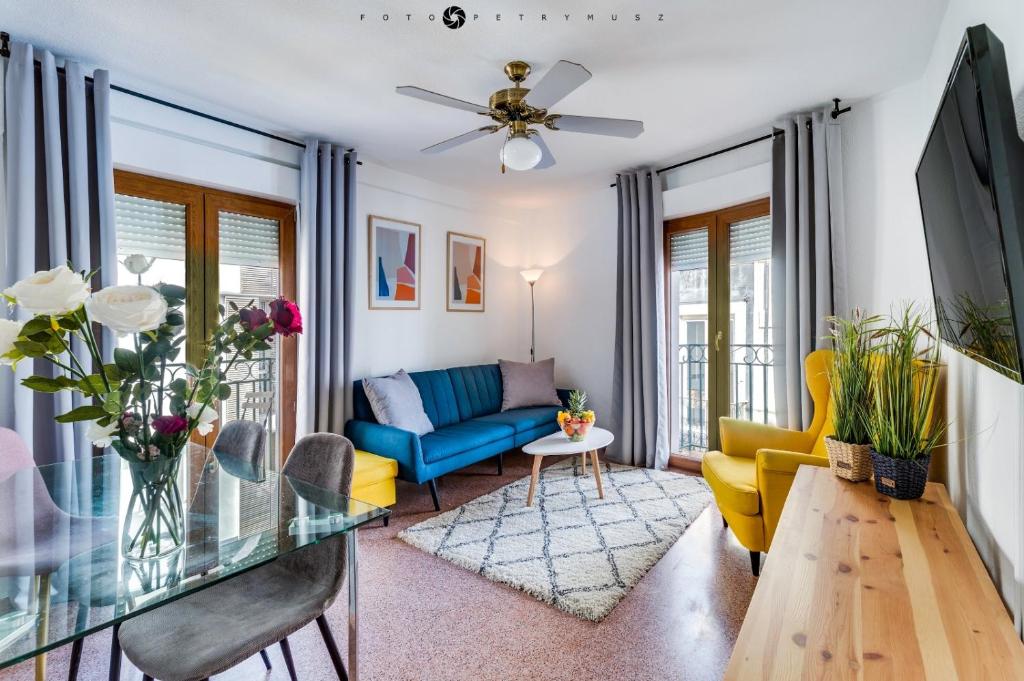 San Nicolas Apartment في أليكانتي: غرفة معيشة مع أريكة زرقاء وكراسي صفراء
