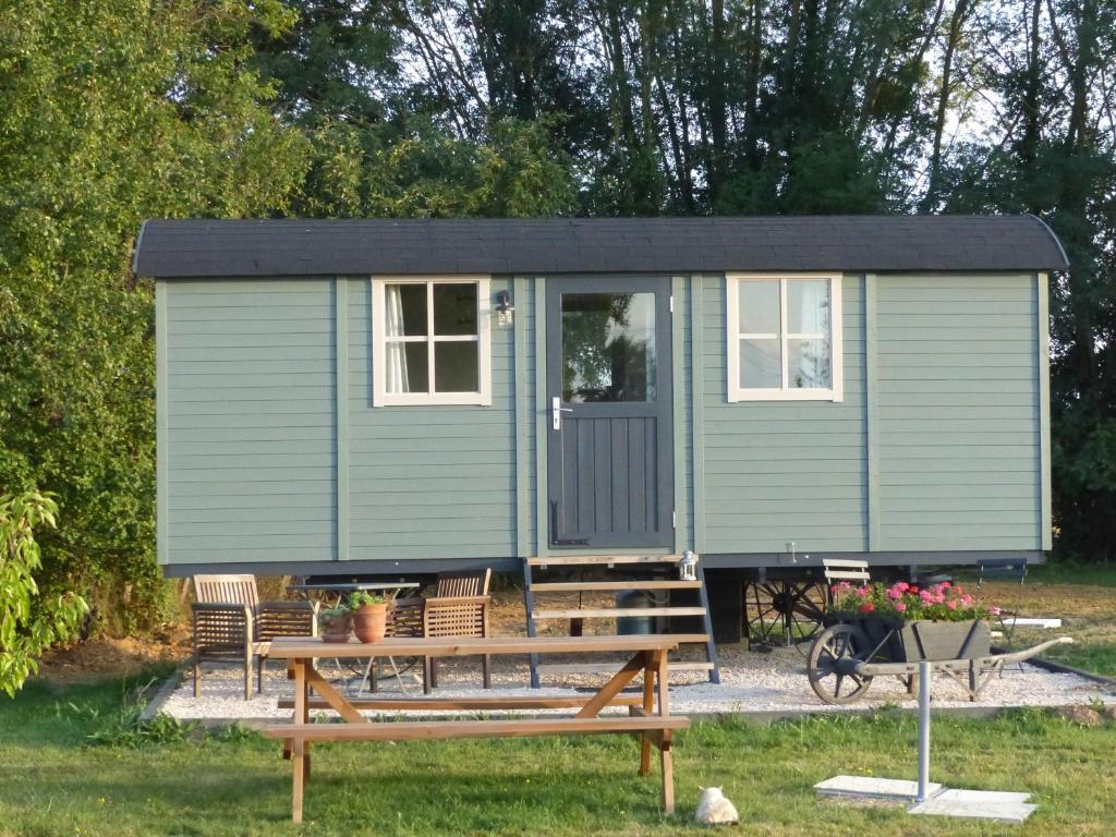 a green tiny house with a table and chairs at les trois bergers in Serley