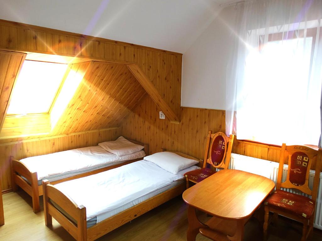 1 dormitorio con 2 camas, mesa y ventana en Ośrodek Wczasowy Zielona Gospoda en Przesieka