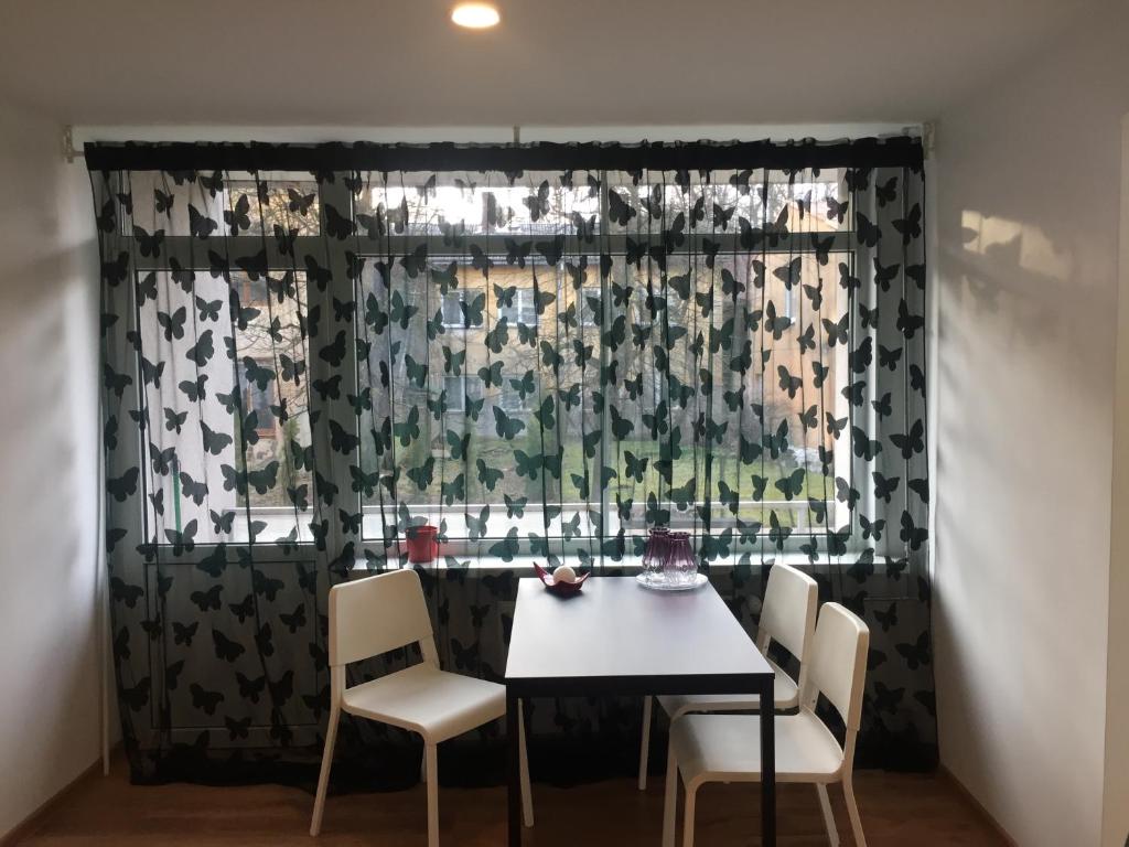 comedor con mesa, sillas y ventana en apartamenti Zirnis en Cēsis