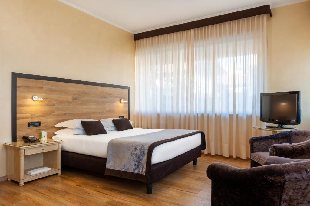 ビエッラにあるAugustus Hotelのベッドとテレビ付きのホテルルーム