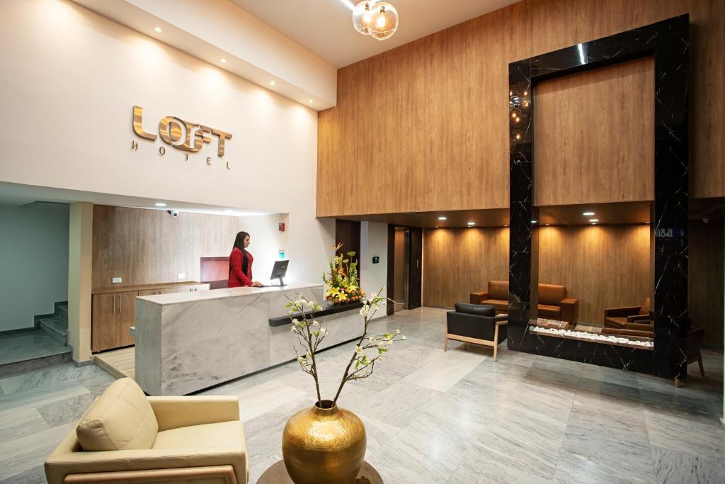 a woman standing in a lobby with a fireplace at Loft Hotel Ipiales in Ipiales