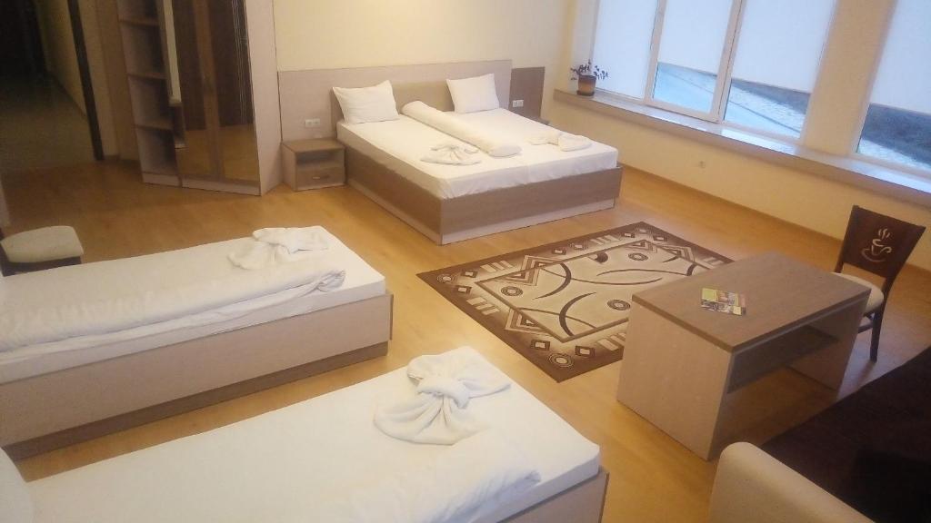 een woonkamer met 2 bedden en een tafel bij Hotel Lago Peshtera in Peshtera