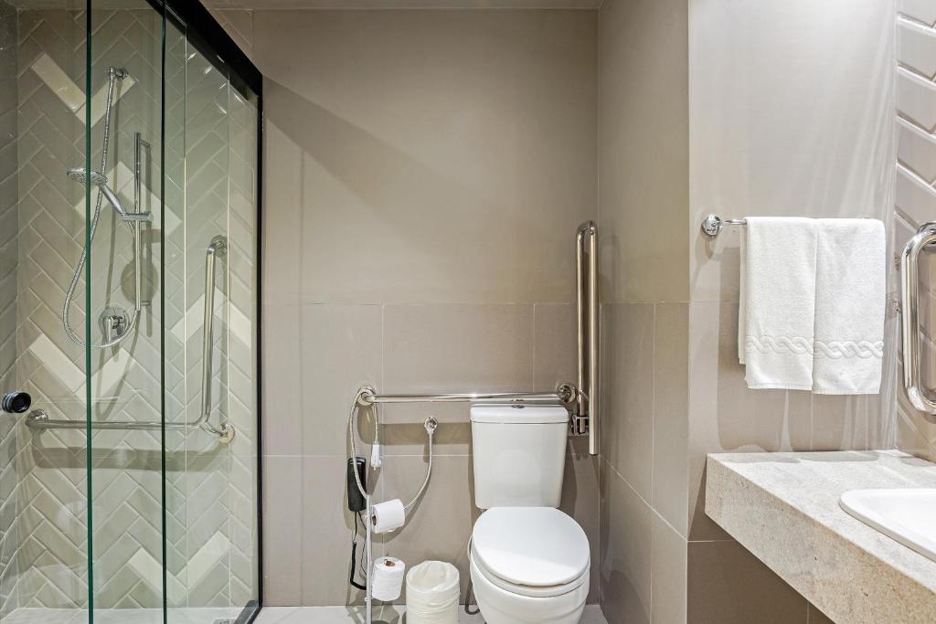 a bathroom with a toilet and a glass shower at Slim Curitiba Alto da XV in Curitiba