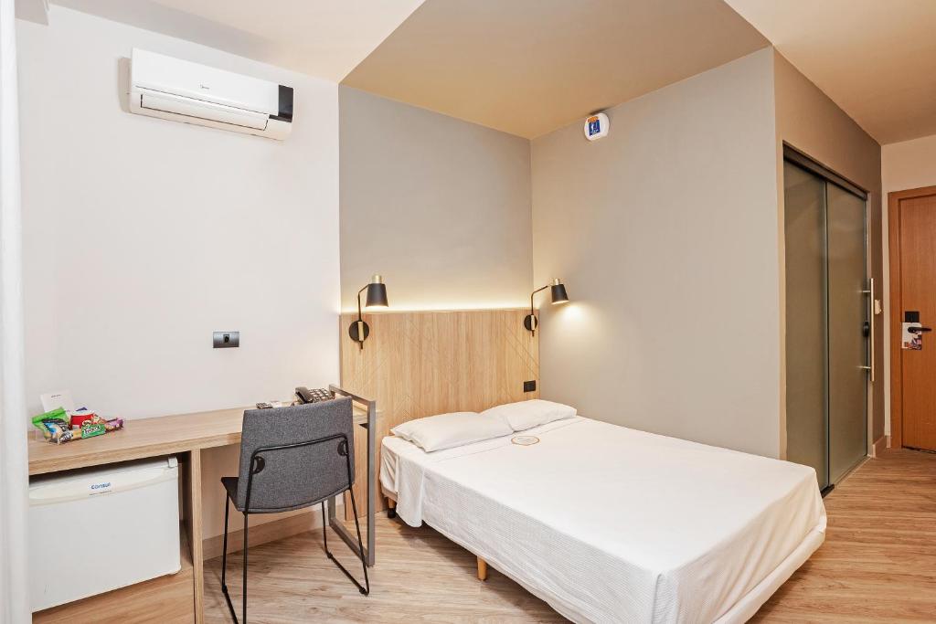 a bedroom with a bed and a desk and a desk at Slim Curitiba Alto da XV in Curitiba
