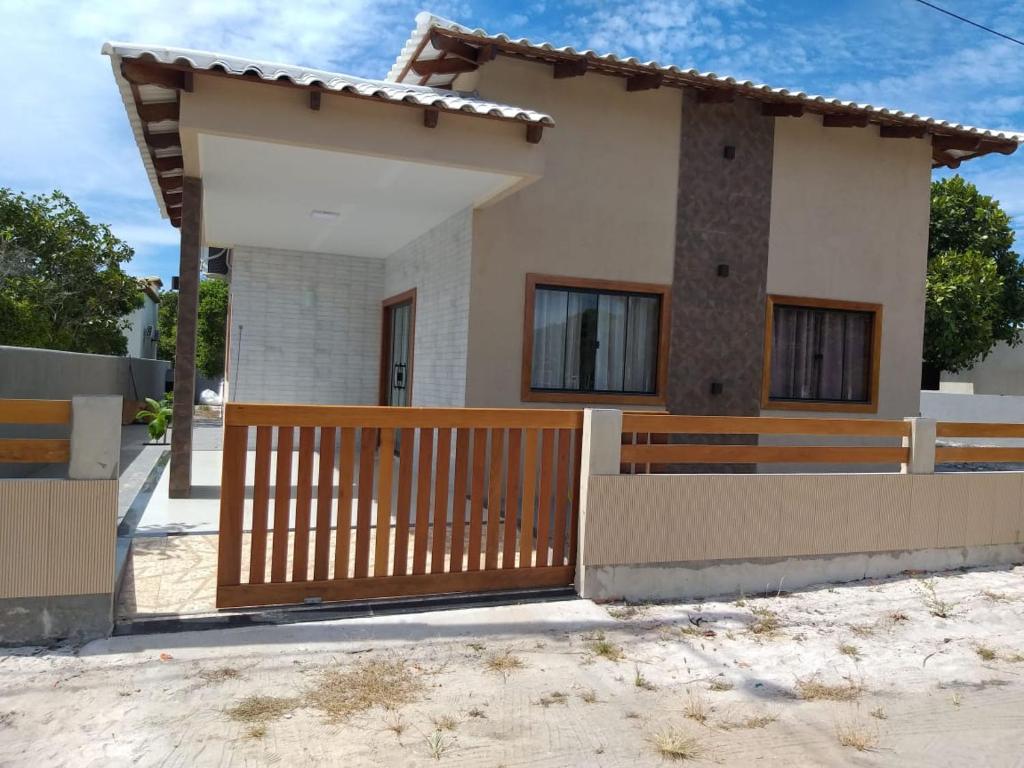 uma casa com um portão de madeira em frente em Casa de praia no Condomínio Guaratiba, Prado-BA em Prado