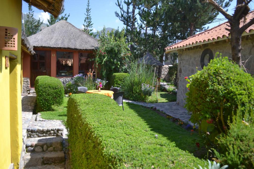 un jardin en face d'une maison avec une haie dans l'établissement Miskiwasi Bed & Breakfast, à Yanque