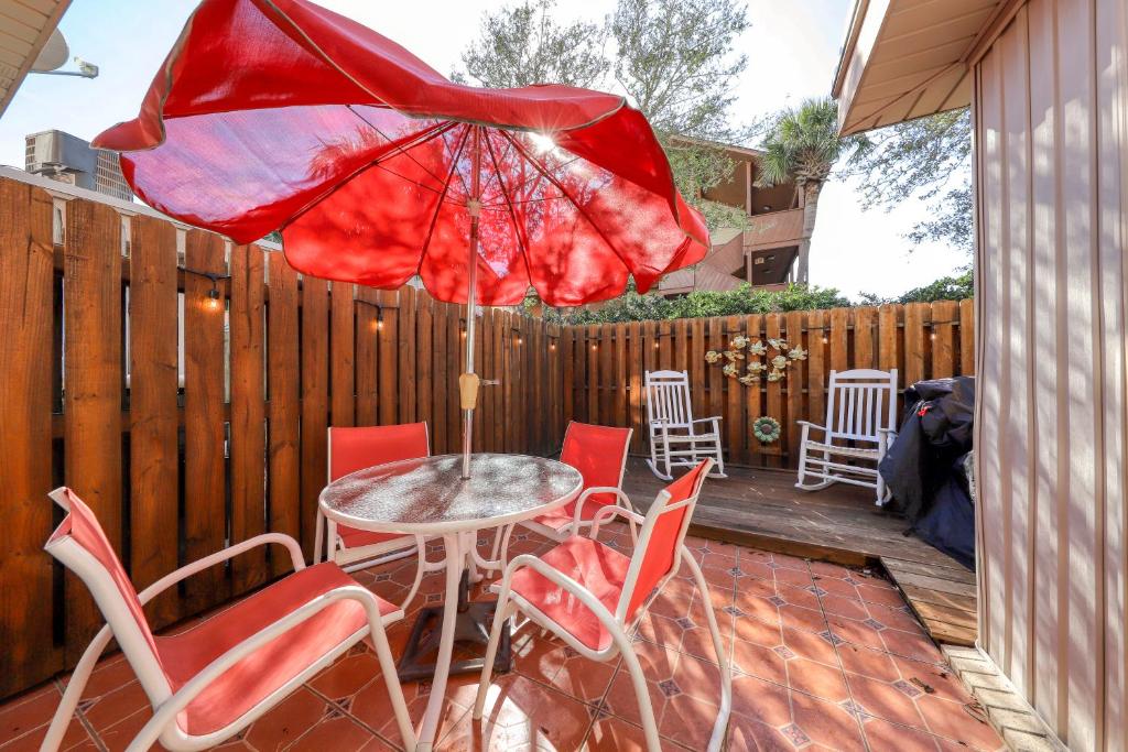 patio con tavolo, sedie e ombrellone rosso di Porcher Villas a Myrtle Beach