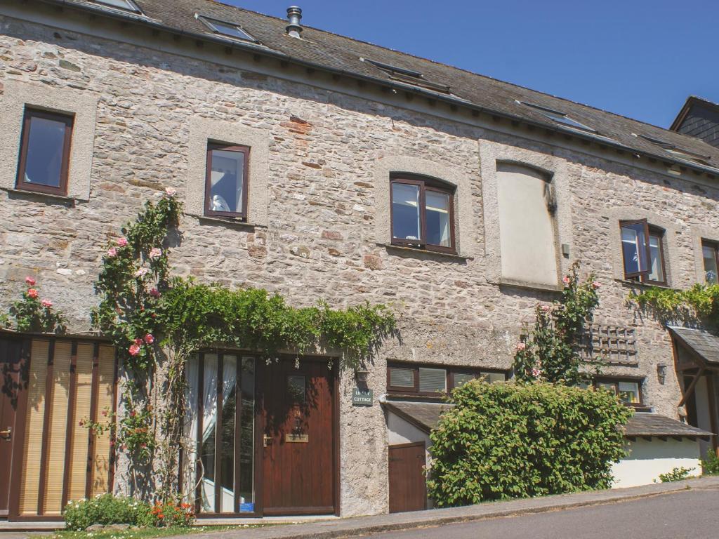 ein altes Backsteinhaus mit Fenstern und Pflanzen in der Unterkunft Linney Cottage in Dittisham