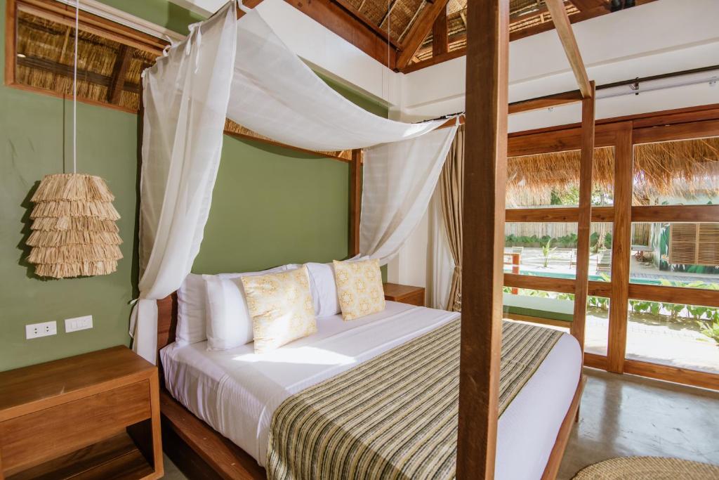 a bedroom with a canopy bed and a window at Las Palmas Villas and Casitas Siargao in General Luna