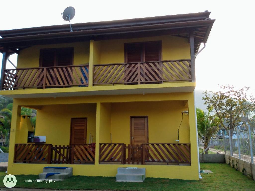 Una casa amarilla con balcones de madera. en Casa na praia do estaleiro, en Ubatuba