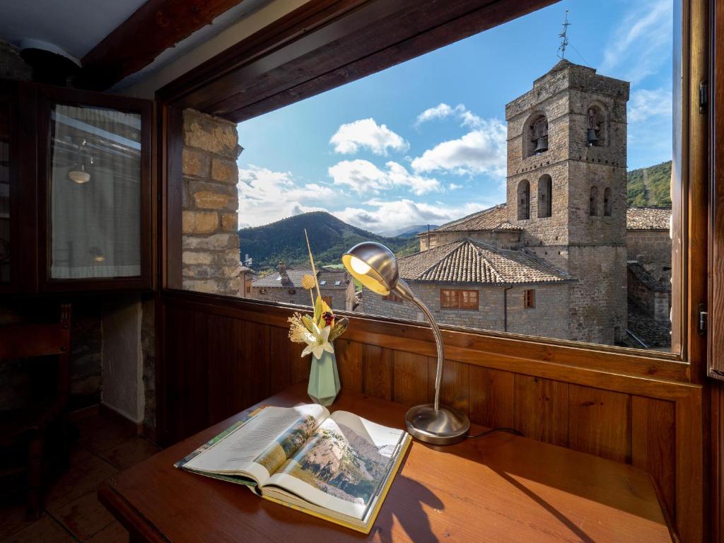 a desk with a lamp and a book in front of a window at CASA RURAL CRUZ - Self check-in in Boltaña