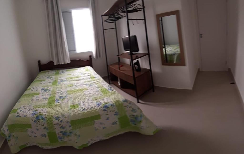 a bedroom with a bed and a television and a mirror at Apartamento Martinica 2 in Caraguatatuba