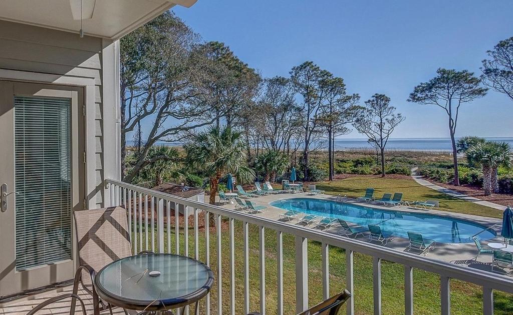a balcony with a table and chairs and a swimming pool at Direct Oceanfront Private Villa Overlooking Pool/Beach - South Forest Beach - Right next to Coligny Plaza in Hilton Head Island