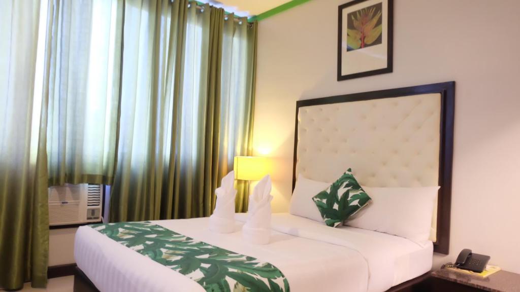 a bedroom with a large white bed with green curtains at GREEN BANANA BUSINESS HOTEL in Davao City