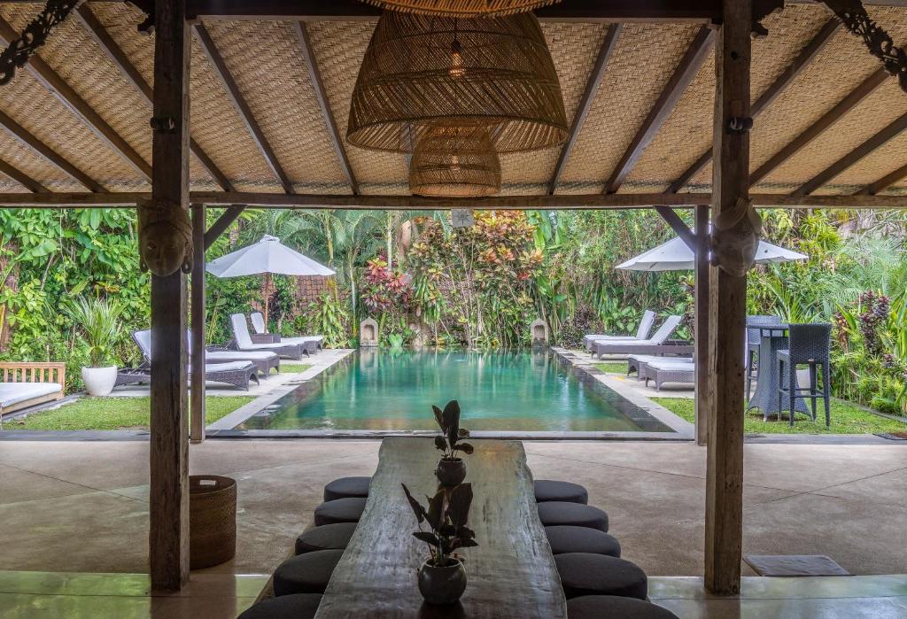 a pool in a resort with lounge chairs and a table at Naya Ubud in Ubud