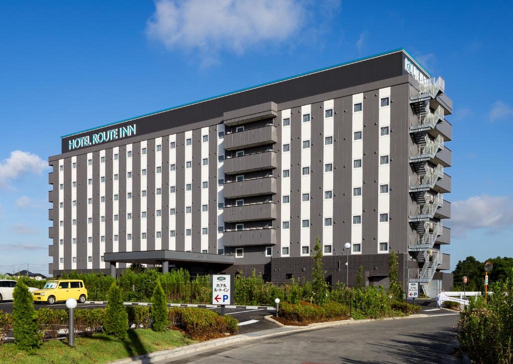 un edificio de hotel con un coche amarillo estacionado frente a él en Hotel Route-Inn Kashiwa Minami -KOKUDO 16GOU ZOI-, en Kashiwa