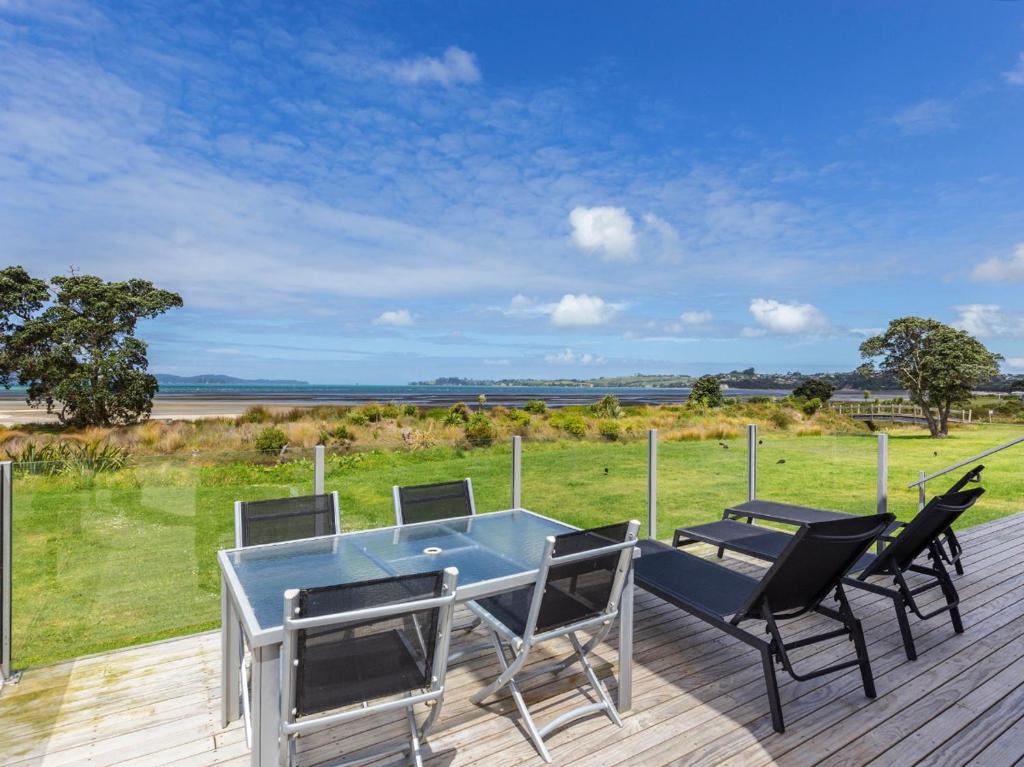 a patio with a table and chairs on a deck at Beachfront Escape - Snells Beach Holiday Home in Snells Beach