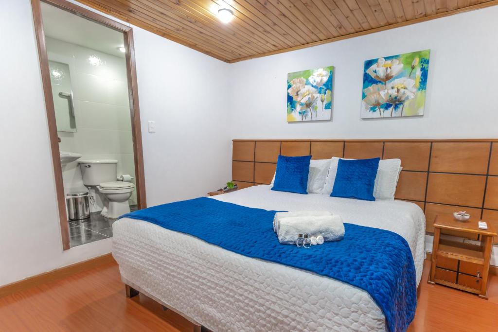 a bedroom with a large bed with blue and white sheets at Hotel Casa Quinta Embajada in Bogotá