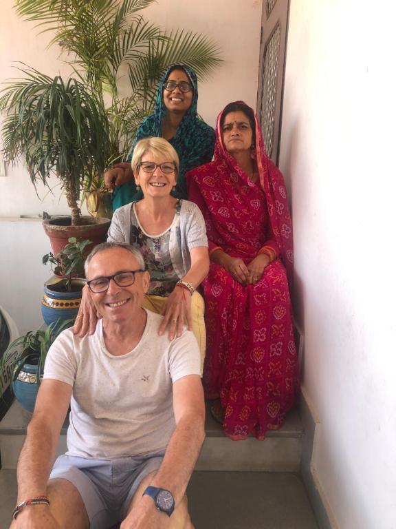 Maison Jaipur في جايبور: مجموعة ثلاث نساء ورجل يجلس على الدرج