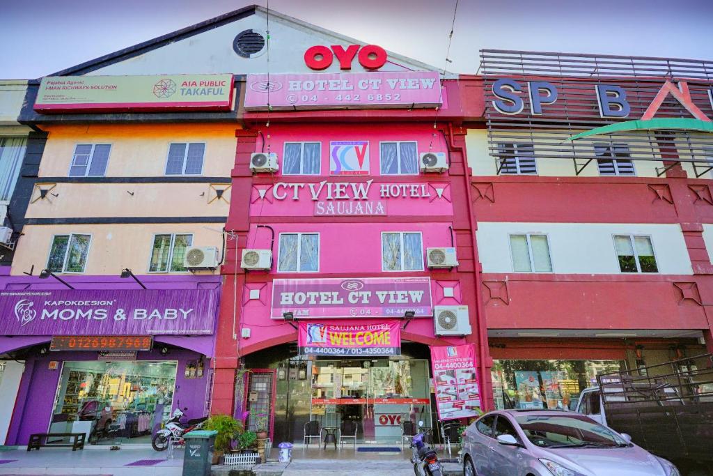 un bâtiment rose avec des panneaux sur son côté dans l'établissement OYO 89710 Saujana CT View Hotel, à Sungai Petani