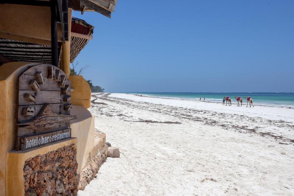 a beach with a building and people on the beach at Blue Marlin Beach Hotel in Diani Beach