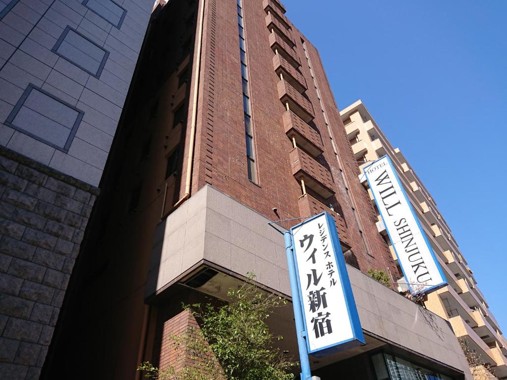 un grand bâtiment avec un panneau devant lui dans l'établissement Residence Hotel Will Shinjuku, à Tokyo