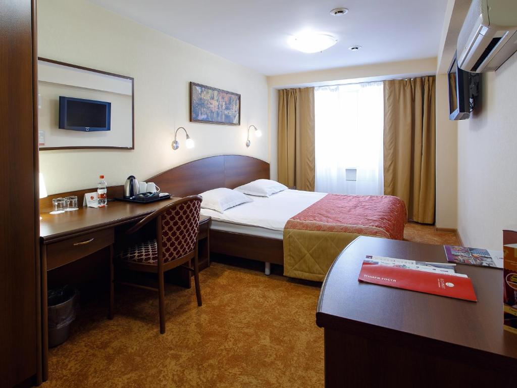 a hotel room with a bed and a desk at AZIMUT Hotel Kemerovo in Kemerovo